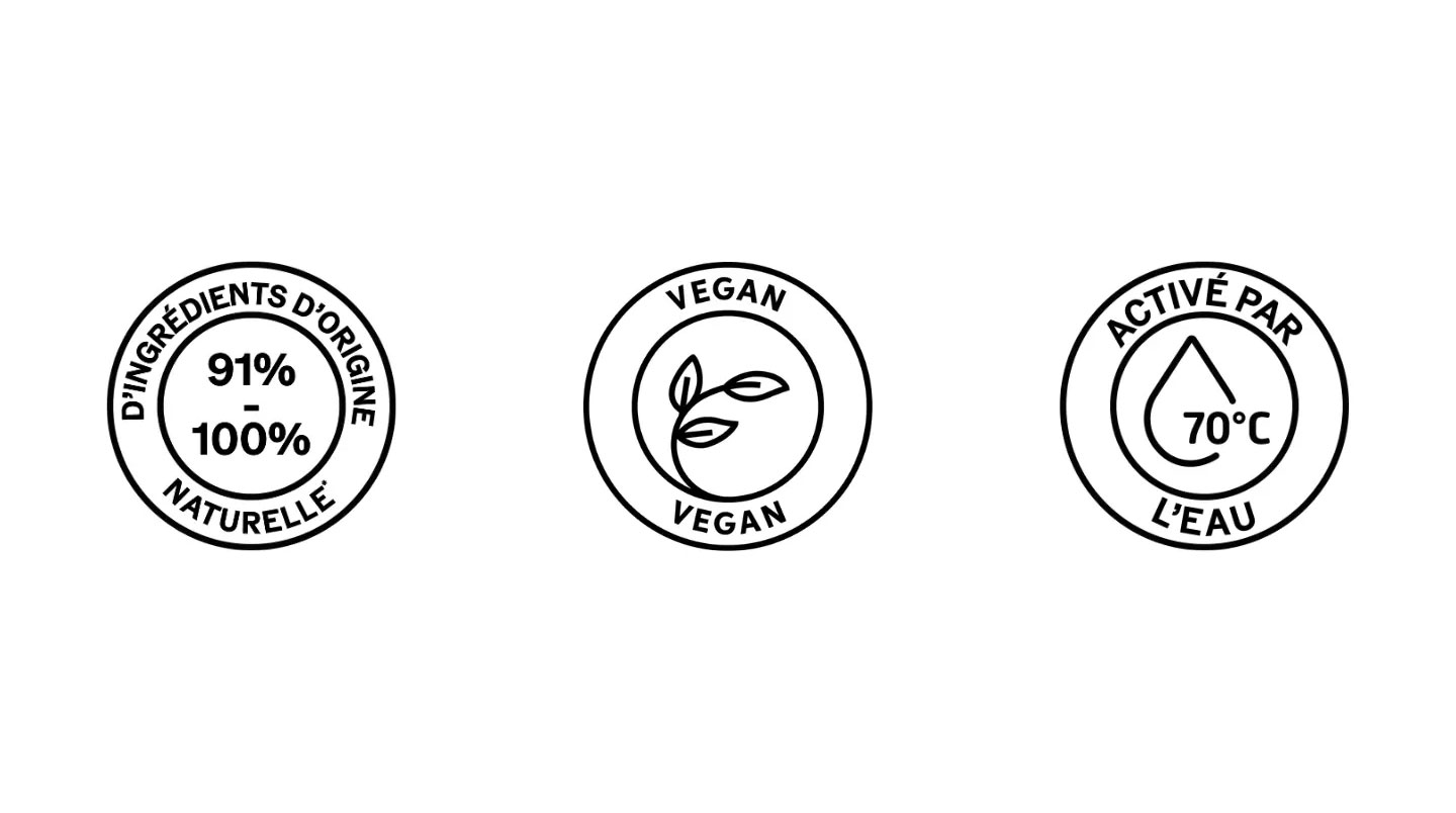 Gros plan sur des étiquettes de produits capillaires véganes posés sur une surface en bois clair, montrant des logos de certification légèrement floutés